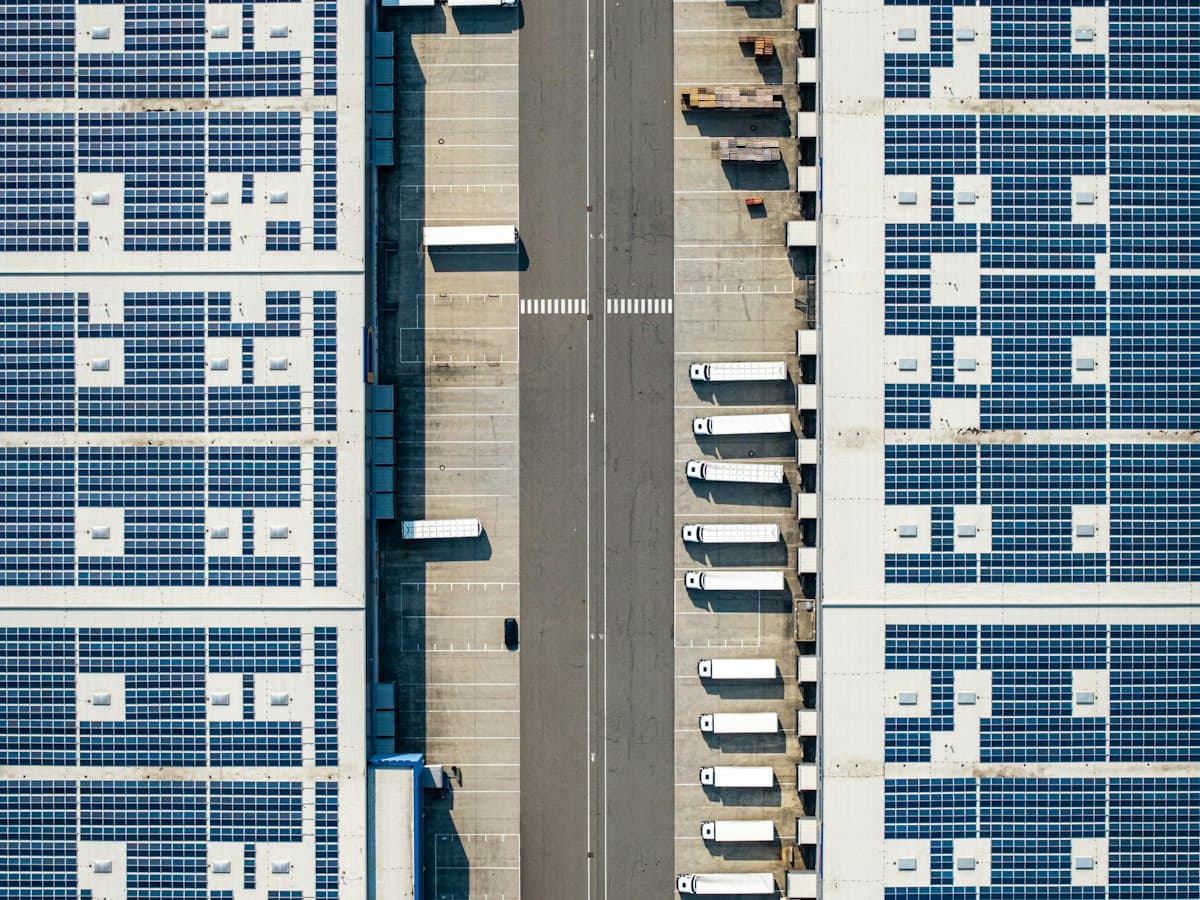 Vista aérea de un centro de distribución con paneles solares en el techo y camiones en los andenes