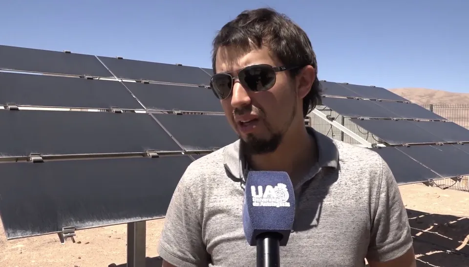 Carlos Jofré entrevistado por la Universidad de Antofagasta frente a paneles solares con polvo, en la Plataforma Solar del Desierto de Atacama